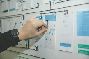 Person pinning a paper on a whiteboard with a map and other documents
